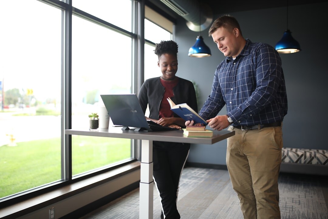 Two colleagues reviewing content on a laptop in a bright office